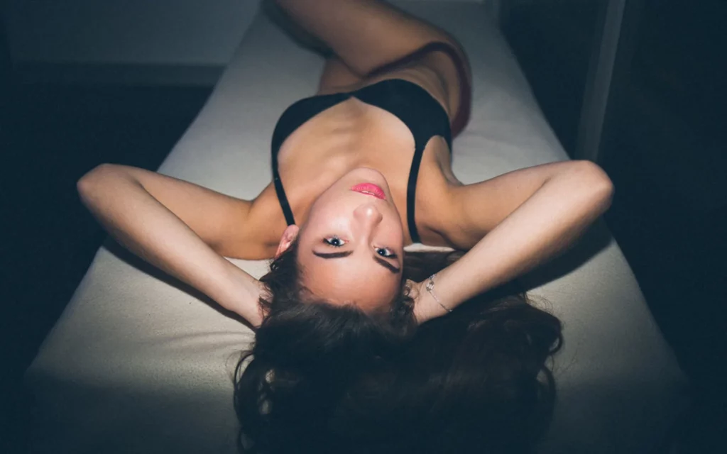 Portrait d'une femme allongée sur un lit regardant l'objectif photographiée par Antoine Cassane.