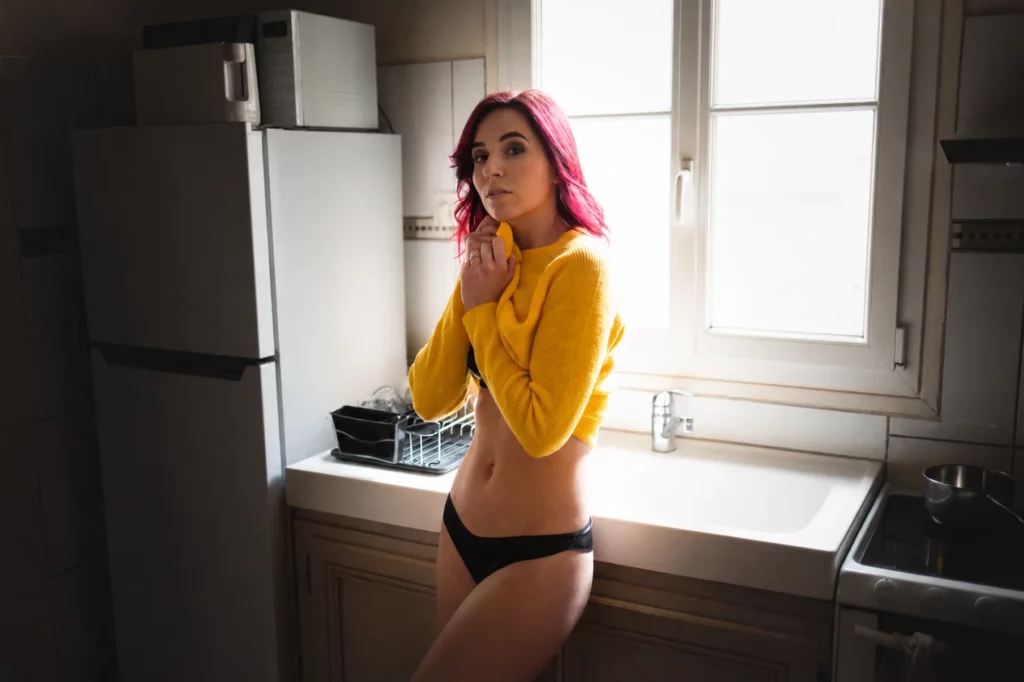 Portrait d'une femme près d'une fenêtre dans une cuisine photographiée par Antoine Cassane.