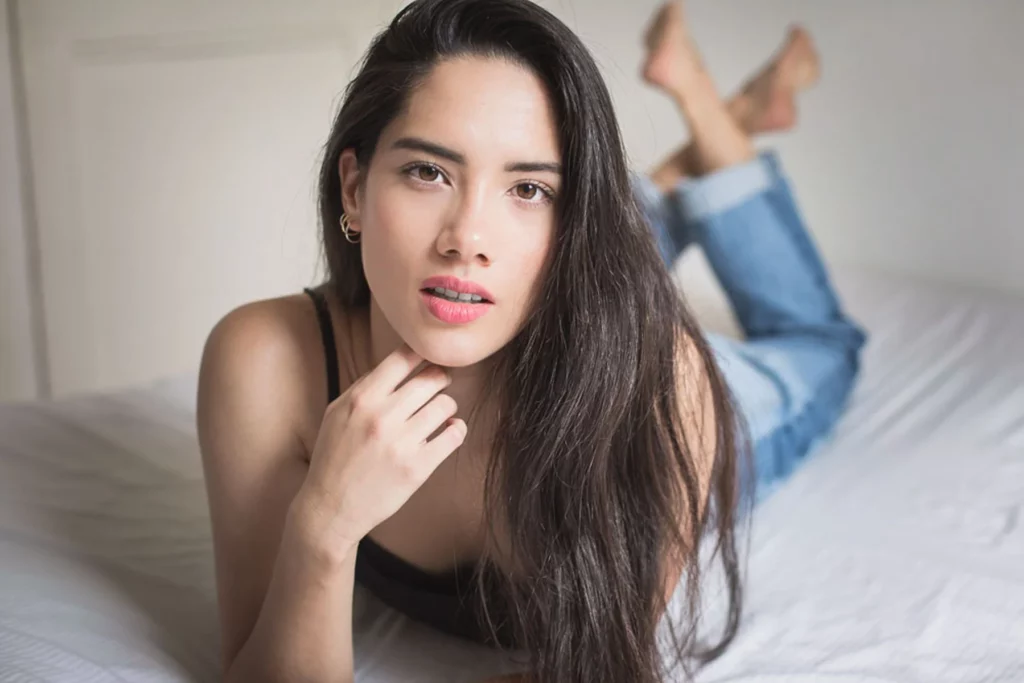 Portrait rapproché d'une femme allongée sur un lit regardant l'objectif photographié par Antoine Cassane.