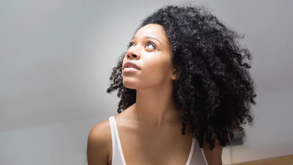 Portrait d'une femme aux cheveux bouclés regardant vers la lumière, réalisé par le photographe Antoine Cassane.