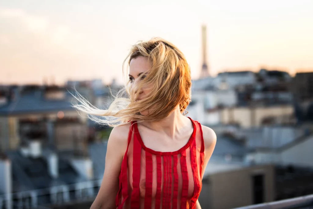 Portrait d'une femme sur un rooftop au coucher du soleil, les cheveux portés par le vent, réalisé par le photographe Antoine Cassane.
