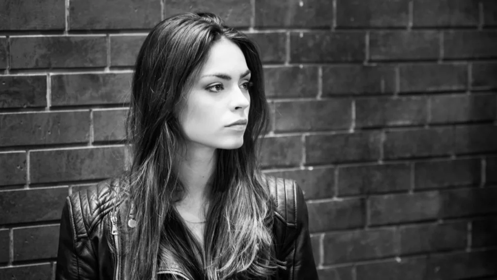 Portrait en noir et blanc d'une femme devant un mur de briques, réalisé par le photographe Antoine Cassane.